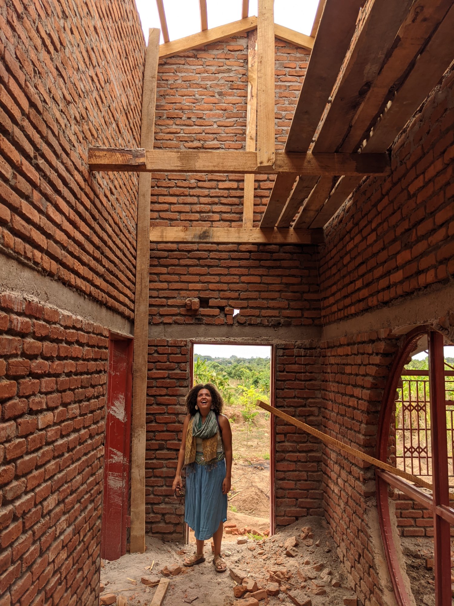 Amari inside the Plateau East house under construction, looking up at the open roof